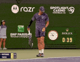 a man holding a tennis racquet in front of a bnp paribas ad