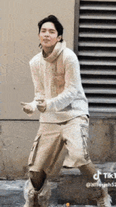 a man in a white sweater and khaki shorts is dancing on a street
