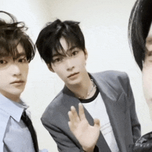 three young men are posing for a picture and one of them is waving at the camera