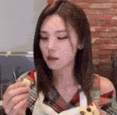 a woman in a plaid shirt is eating a cookie with a fork .