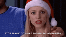 a woman wearing a santa hat is holding a potato in her hands .