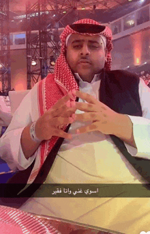 a man wearing a head scarf and a white shirt with arabic writing on the bottom