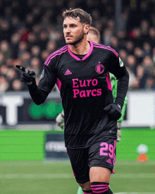 a soccer player wearing a black and pink jersey with euro parcs on it