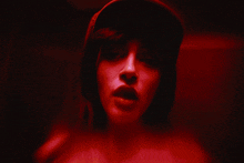 a woman wearing a hat is covering her face with her hands in front of a red background