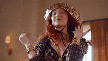 a woman with red hair is wearing a turban and a very revealing top