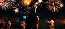 a group of people are watching fireworks in a stadium with a clock that says 1:40