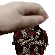 a hand is holding a statue of a man in a red and black armor .