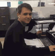 a man wearing ear buds is sitting at a desk in front of a computer