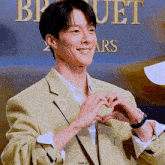 a man in a yellow jacket making a heart shape with his hands