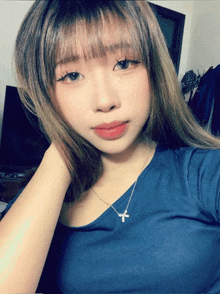 a woman wearing a blue shirt and a necklace with a cross on it