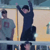 a man in a black hat is dancing in front of a crowd with his arms in the air
