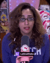 a woman wearing glasses and a hello kitty microphone says latinaotaku on the bottom right