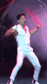 a man in a white shirt and pants is dancing on a stage
