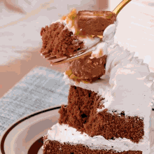a slice of chocolate cake with whipped cream and nuts is being eaten with a fork