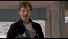 a man with a mustache is standing in front of a window in a room holding a glove .