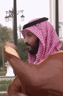 a man with a beard wearing a keffiyeh and robe
