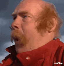 a bald man with a mustache wearing a red jacket