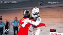 two racers are hugging each other in front of a sign that says 50