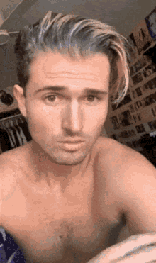 a shirtless man with blue hair makes a funny face