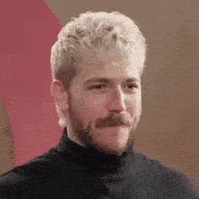 a man with blonde hair and a beard is making a surprised face with his mouth open .