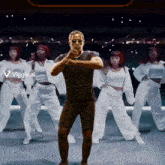 a man is standing in front of a group of dancers with a viggle.ai logo on the bottom right