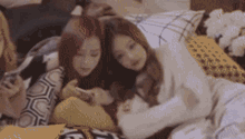 a group of young women are laying on a bed looking at their phones .