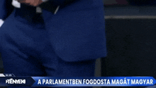 a television screen shows a news report about a parliamentben fogdosta magat magyar
