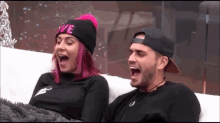 a man and woman are sitting on a couch with their mouths open