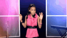 a girl in a pink top stands in front of a keyboard and guitar
