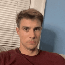 a man is making a funny face while taking a selfie in front of a window .