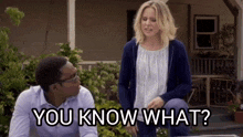 a man and woman are standing in front of a house and the woman is asking the man " you know what "