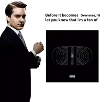 a man in a suit and tie is standing next to a poster that says ' before it becomes overrated '