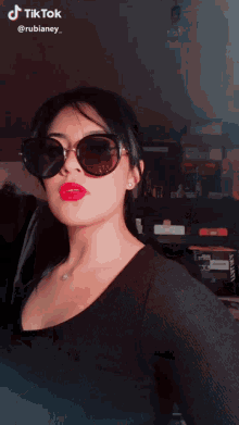 a woman wearing sunglasses and red lipstick has a tiktok watermark on her face
