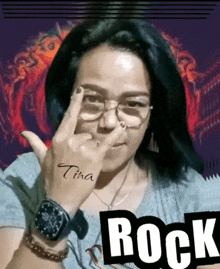 a woman wearing glasses and a watch shows a middle finger with the name tina written on her wrist