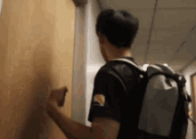 a man with a backpack is standing in a hallway .