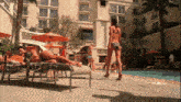 a woman in a bikini stands in front of a pool