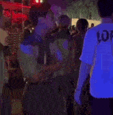 a man wearing a shirt that says lof stands in a crowd of people .