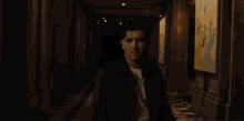 a man is walking down a dark hallway with a painting on the wall