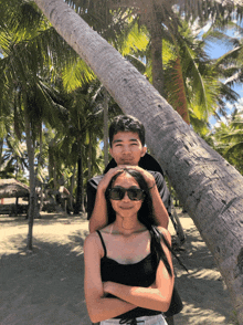 a man and a woman are posing for a picture under palm trees