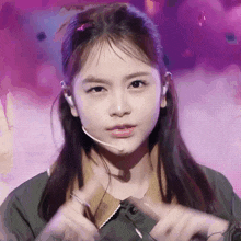 a young girl wearing a microphone looks at the camera