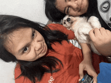 a girl wearing a red shirt that says piko holds a small white dog