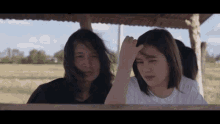 two women are standing next to each other under a wooden roof .