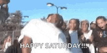 a group of people are standing in a crowd with the words `` happy saturday '' written in white letters .