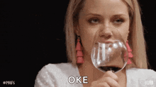 a woman is holding a glass of wine in her hand .