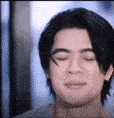 a young man with his eyes closed is making a funny face .