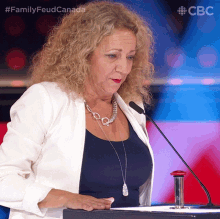 a woman stands at a podium with a microphone and the words family feud canada on the bottom