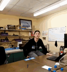 a man sits at a desk in front of a white board that says " dept "