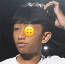 a young boy with a yellow smiley face on his eye is looking at the camera .