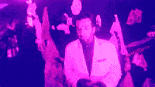 a man in a white suit is standing in a purple room