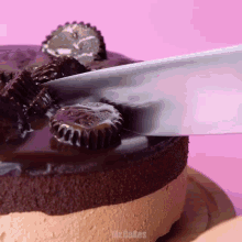 a cake with peanut butter cups on top is being cut with a knife